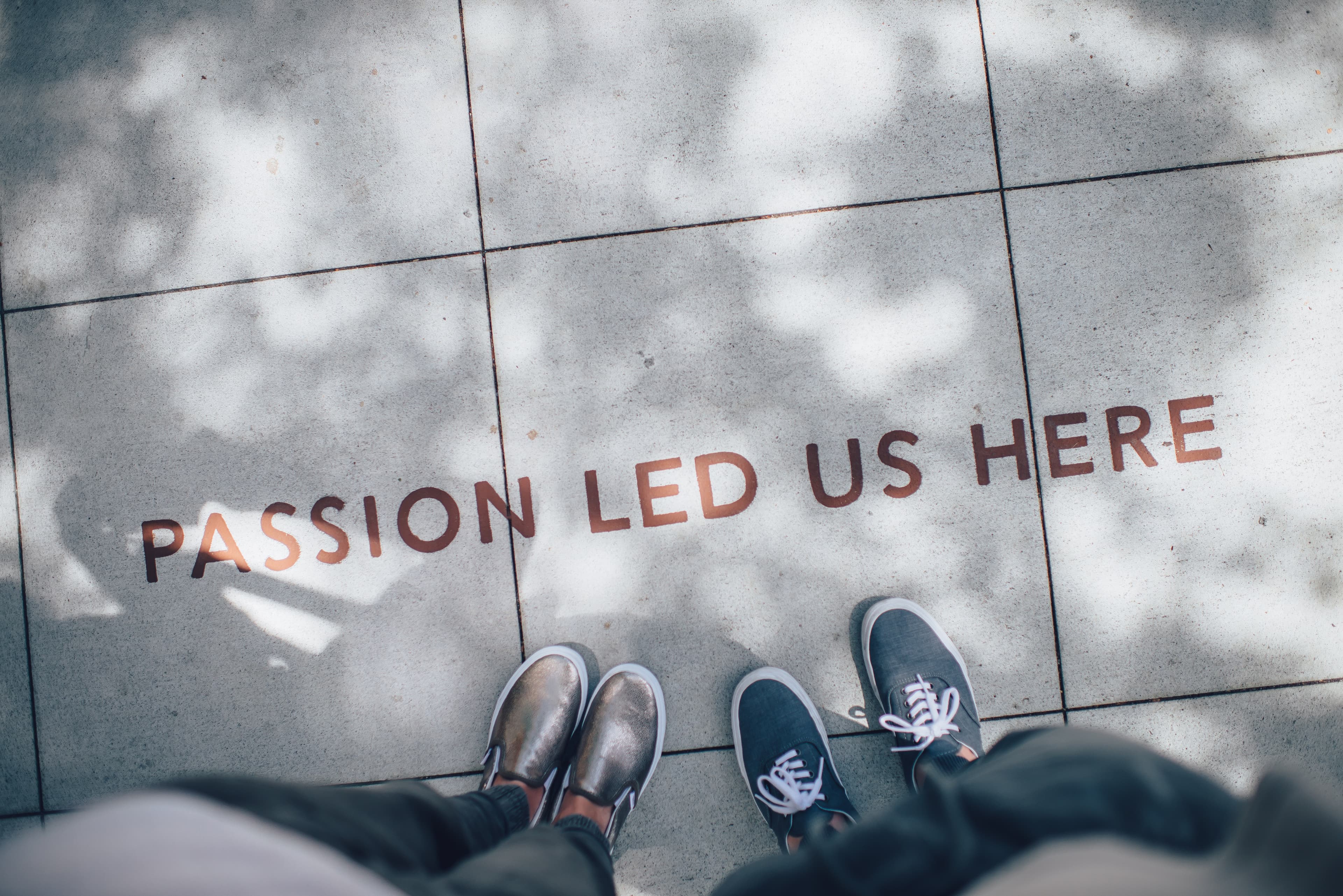 Two people standing and in the floor you read: Passion lead us here
